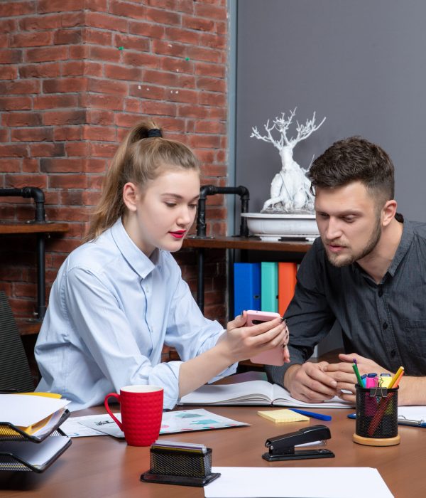 top-view-young-man-his-female-co-worker-sitting-table-discussing-one-issue-office-enviroment (1)